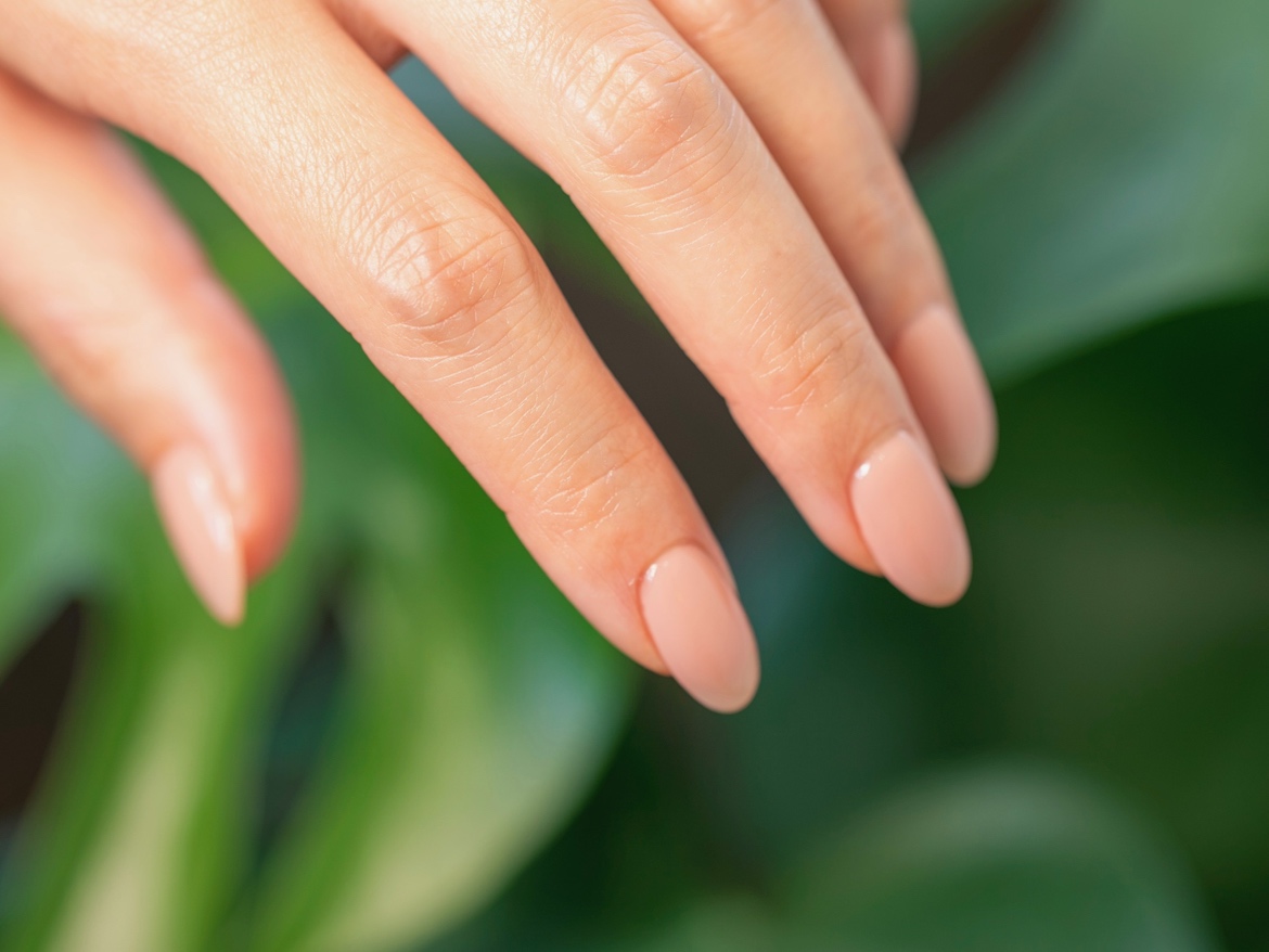 ネイリストが細い筆を使って丁寧にジェルネイルを塗布している施術の様子
